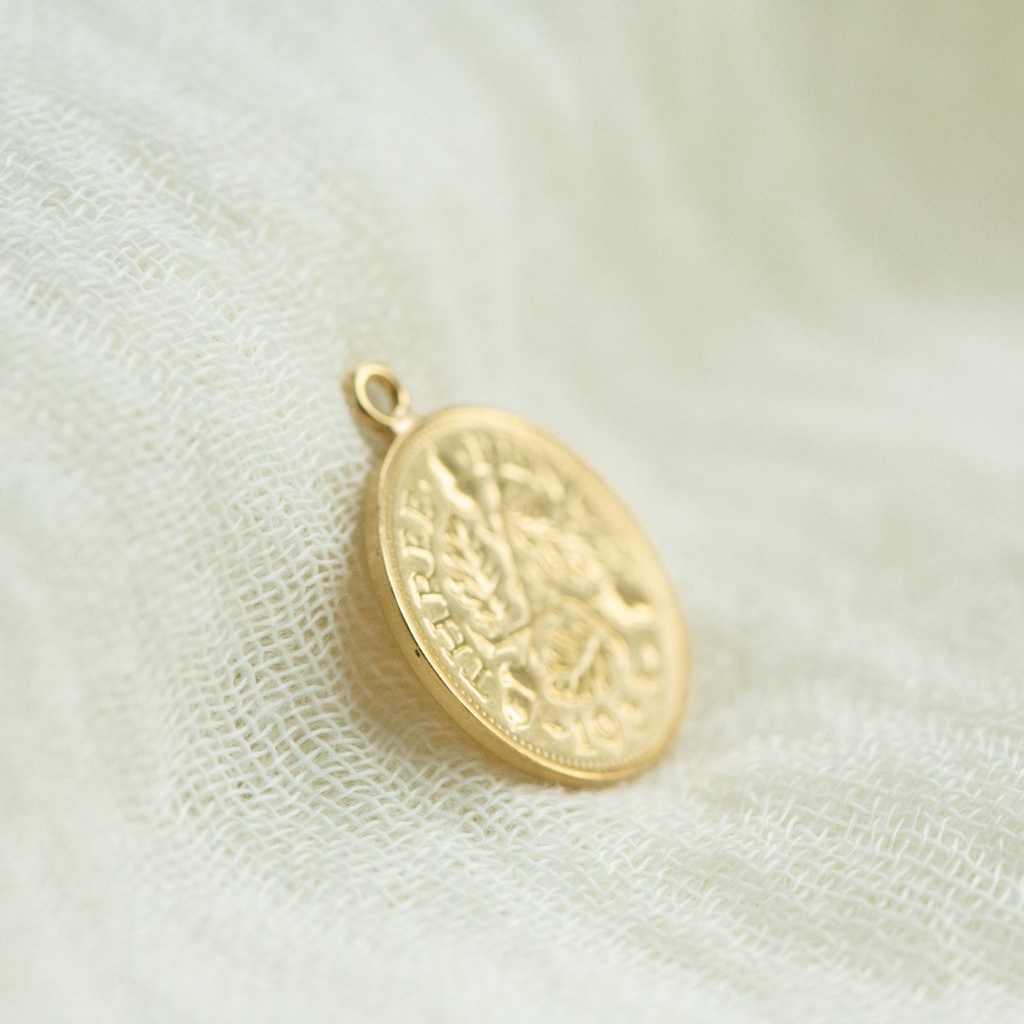 Gold pendant on a textured white fabric background