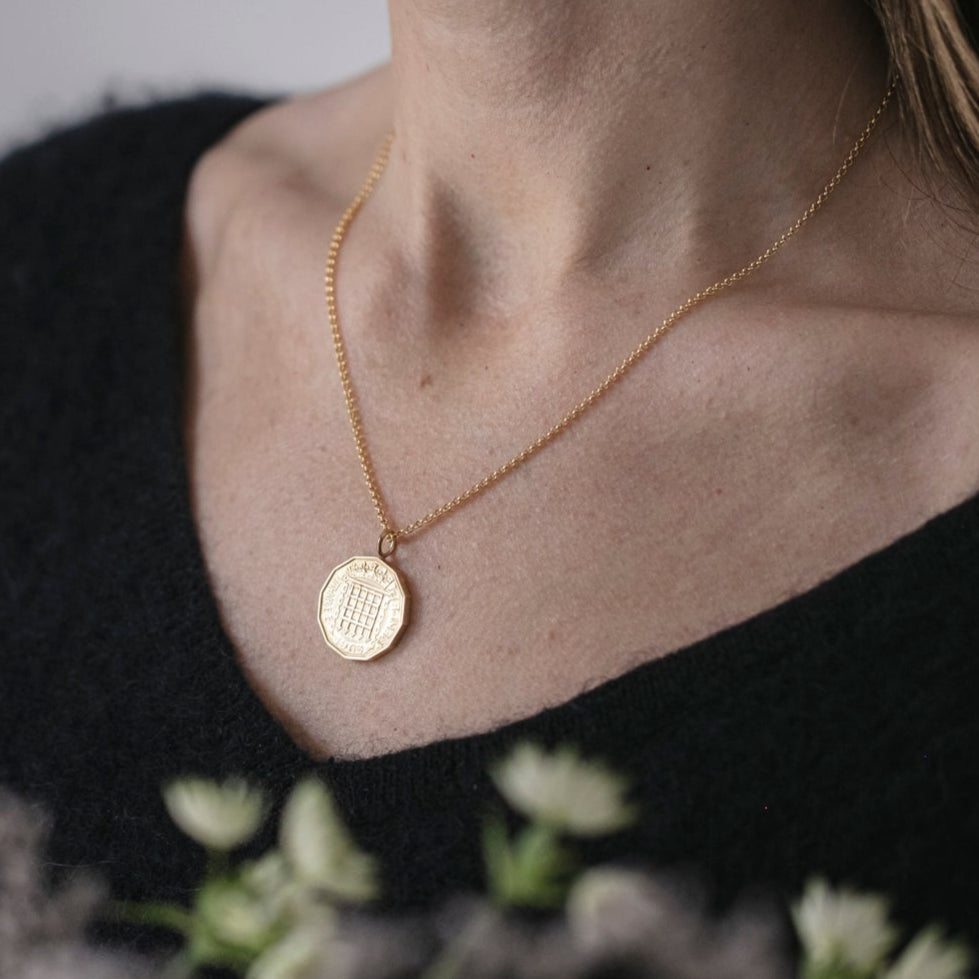 Person wearing a gold coin necklace with a blurred background