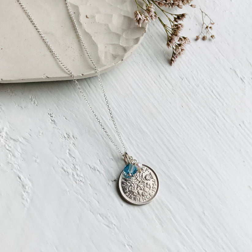 Distant view of 1954 70th birthday BRitish coin necklace, lucky sixpence and March birthstone charm with pearl