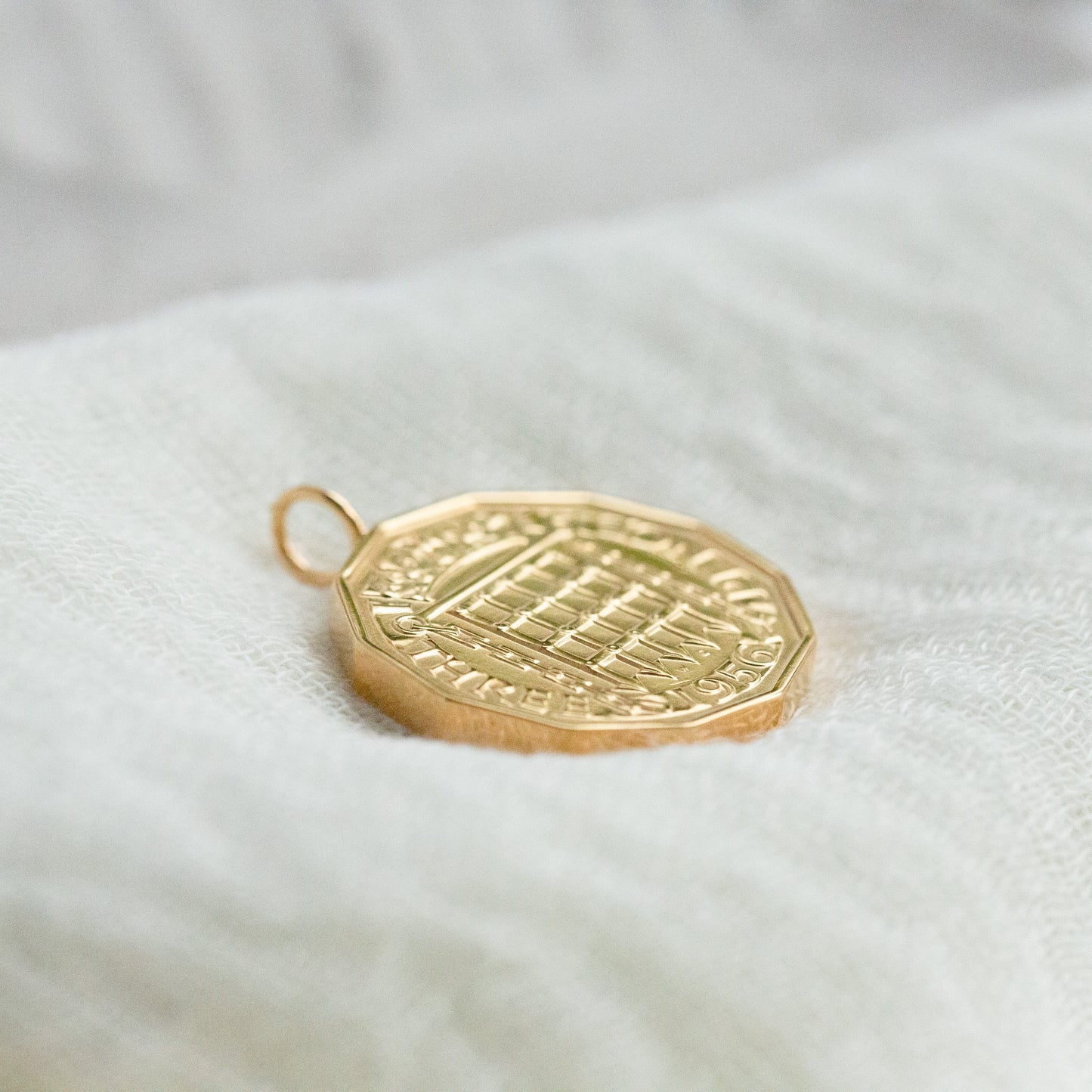 Prenoa Gold coin pendant on a white fabric background