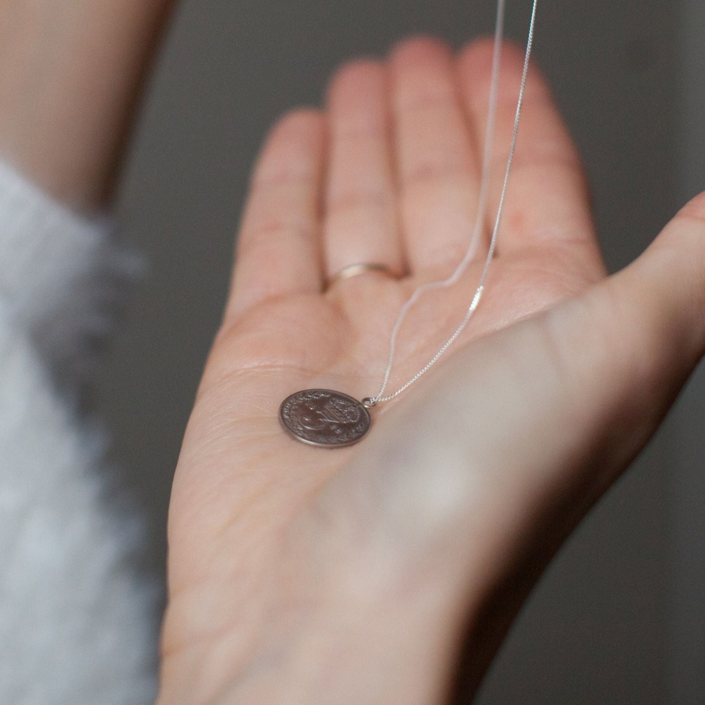 British three pence, with a silver chain, being held in my hand