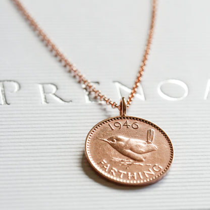 1946 Rose gold necklace with a bronze coin pendant on a white surface