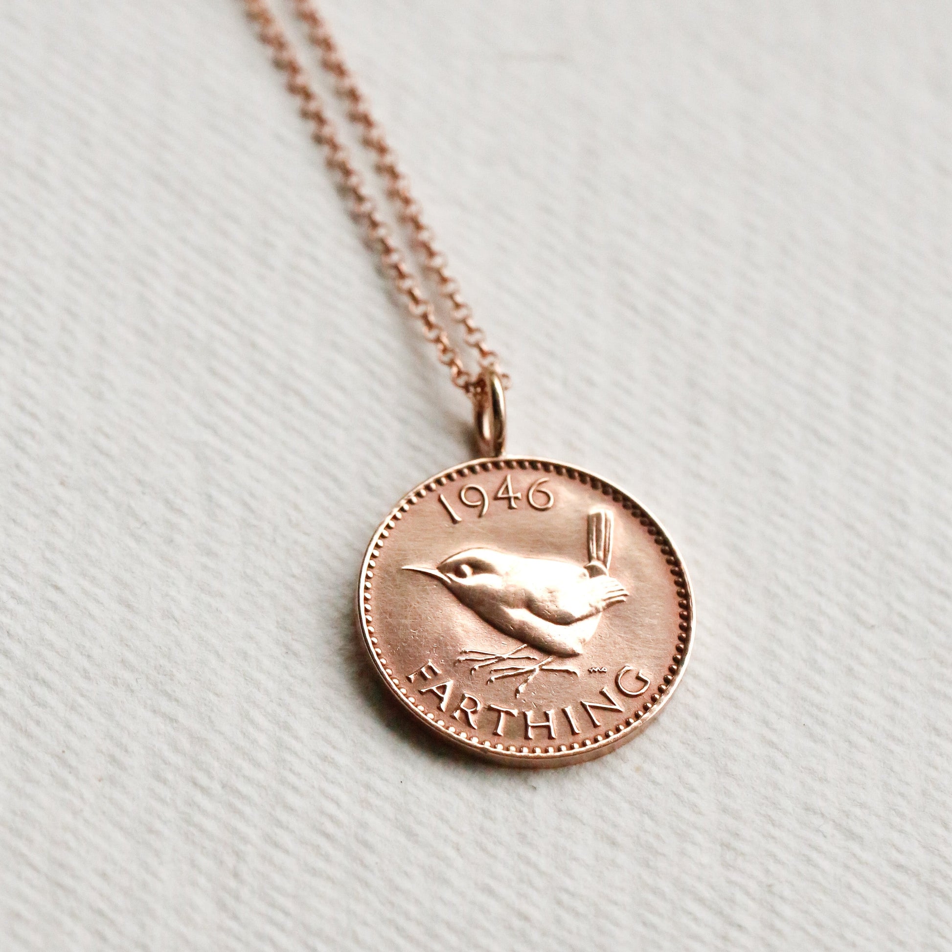 Rose gold necklace with a coin pendant on a light background