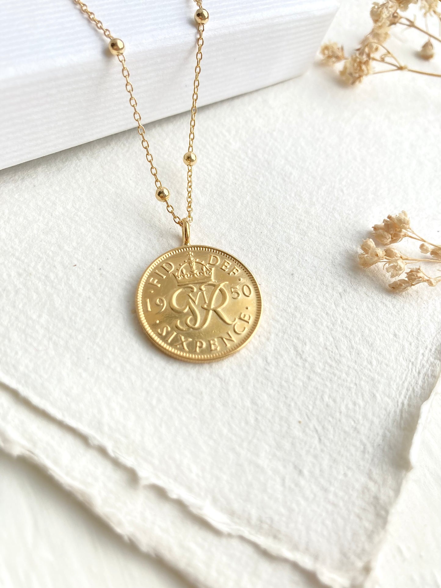 Gold necklace with a coin pendant on a white fabric background