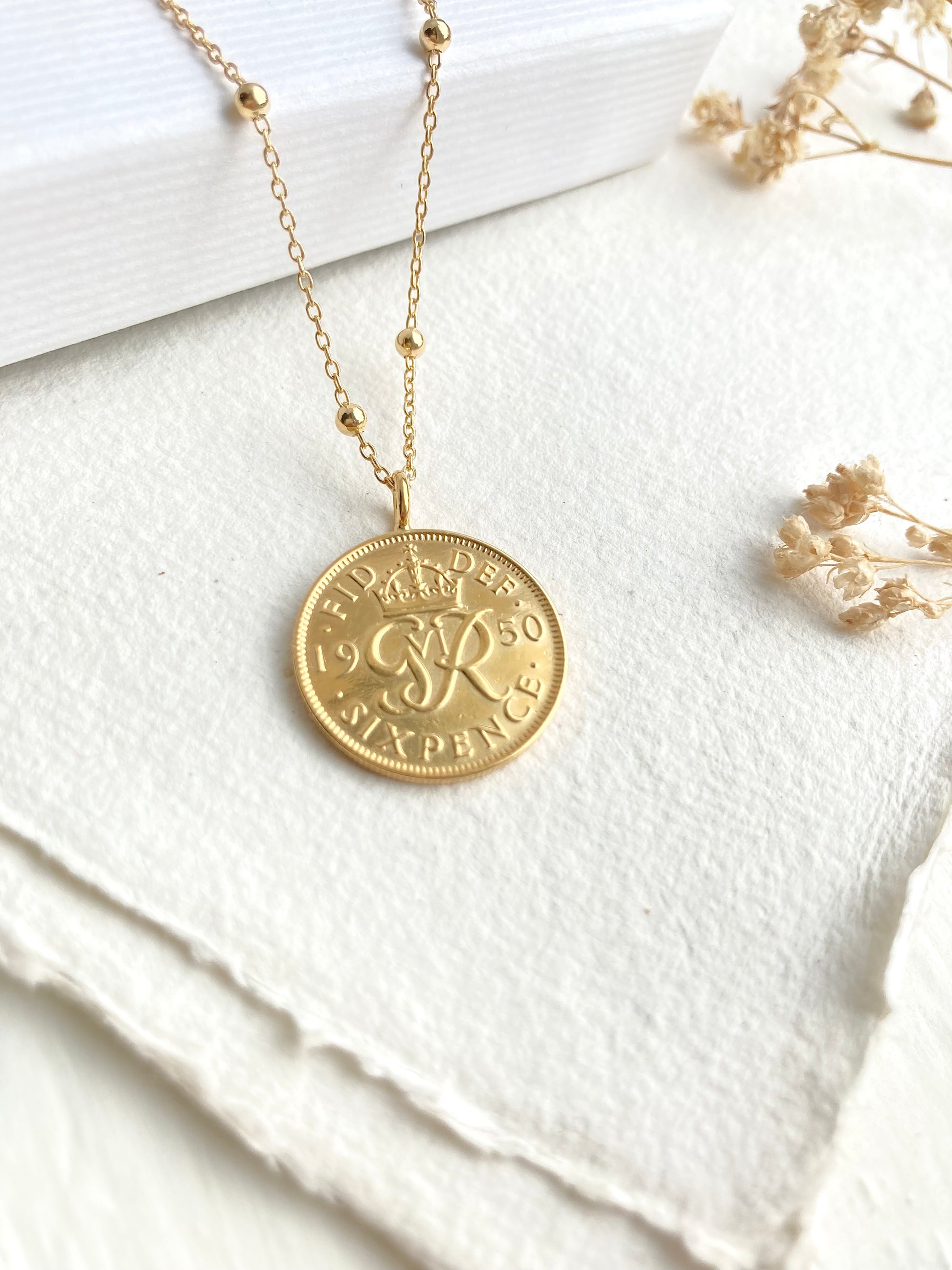 Gold necklace with a coin pendant on a white fabric background