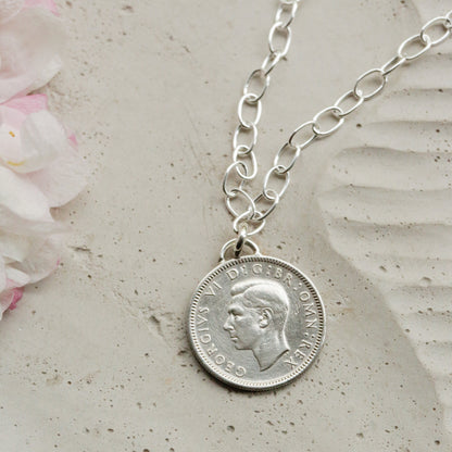 Silver coin oval bracelet with George VI 1951 dated sixpence on a stone surface with flowers
