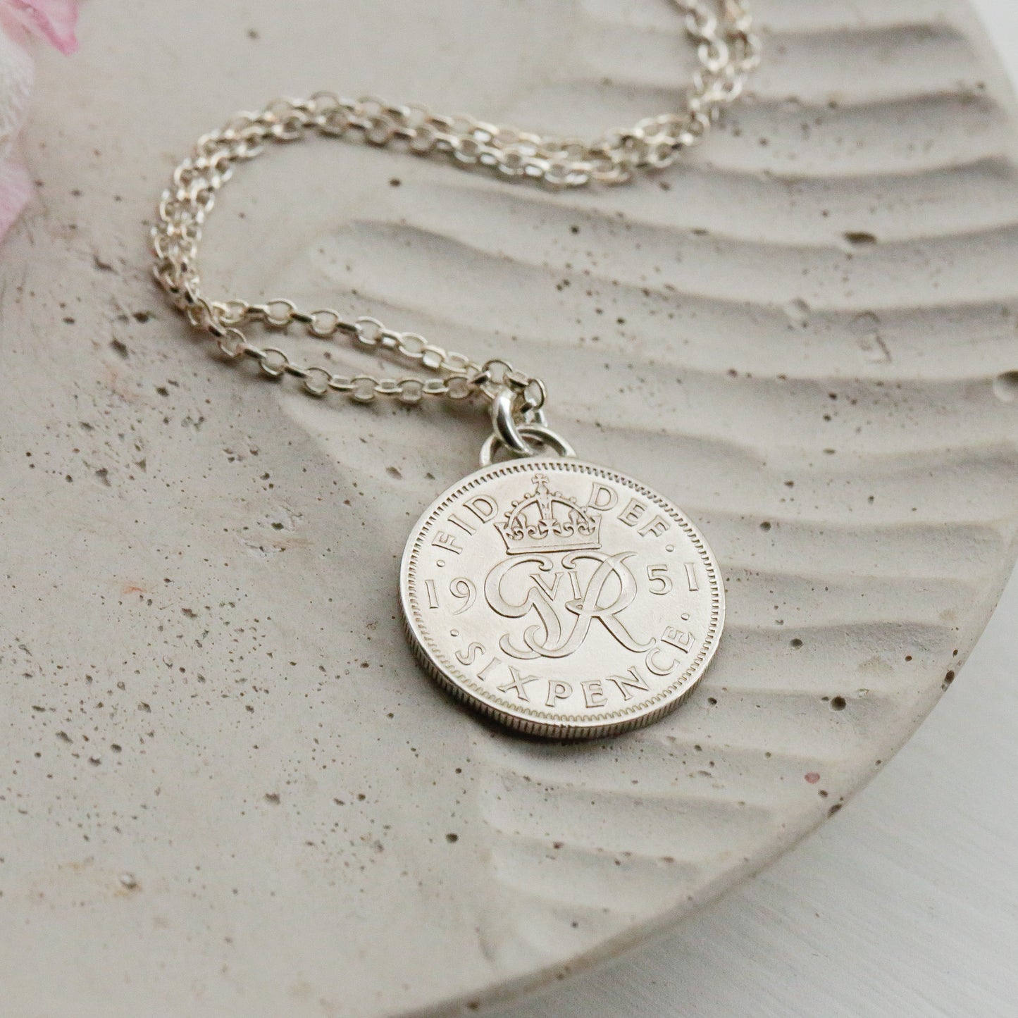Silver coin necklace with a round pendant on a textured surface