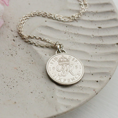 Silver coin necklace with a round pendant on a textured surface