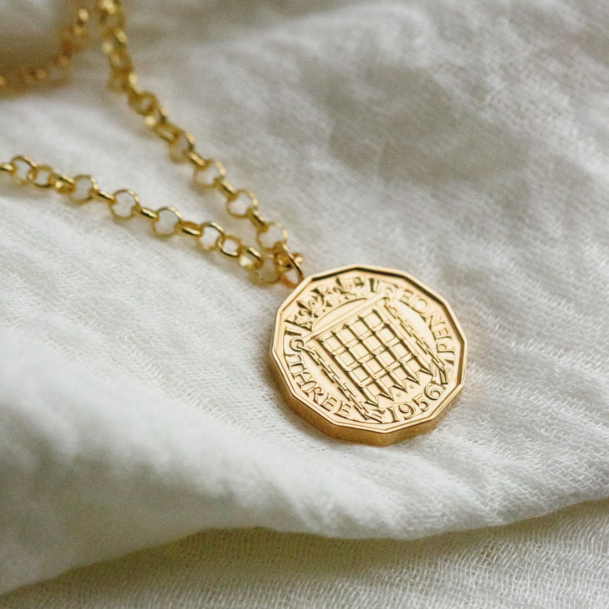 1956 Gold threepence coin necklace with chunky gold chain on a silk background