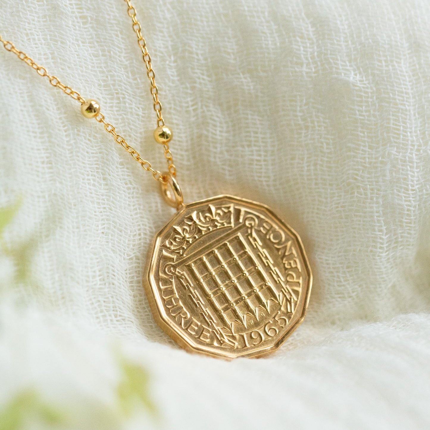 22ct Gold plated necklace with a detailed coin pendant on a soft white fabric background. Gold chain with a satellite detail.