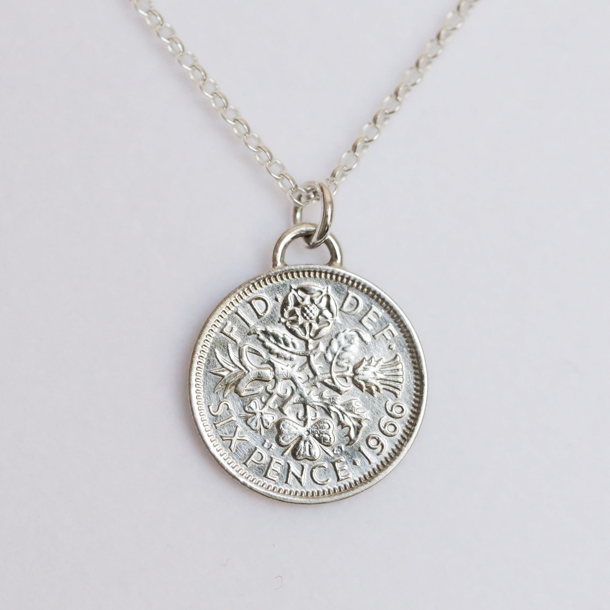 Silver silver coin pendant necklace with a signature arc bail on a light gray background