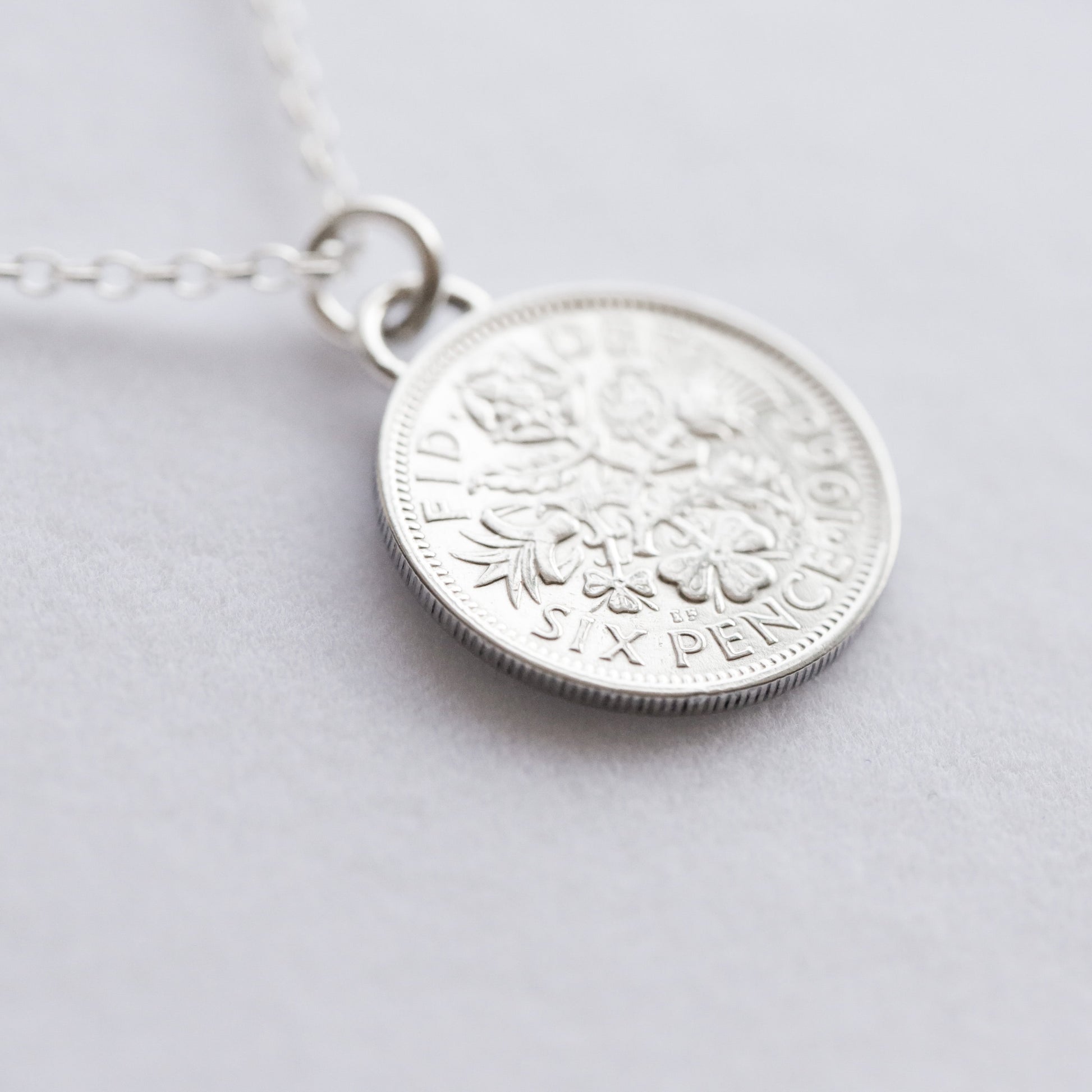 Silver coin pendant necklace on a light gray background