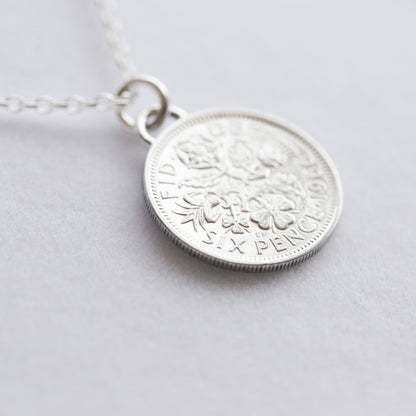 Silver coin pendant necklace on a light gray background