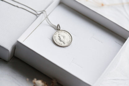 Silver pendant necklace in an open jewelry box on a light wooden surface