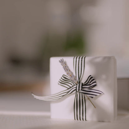 White gift box with a black and white striped ribbon on a blurred background
