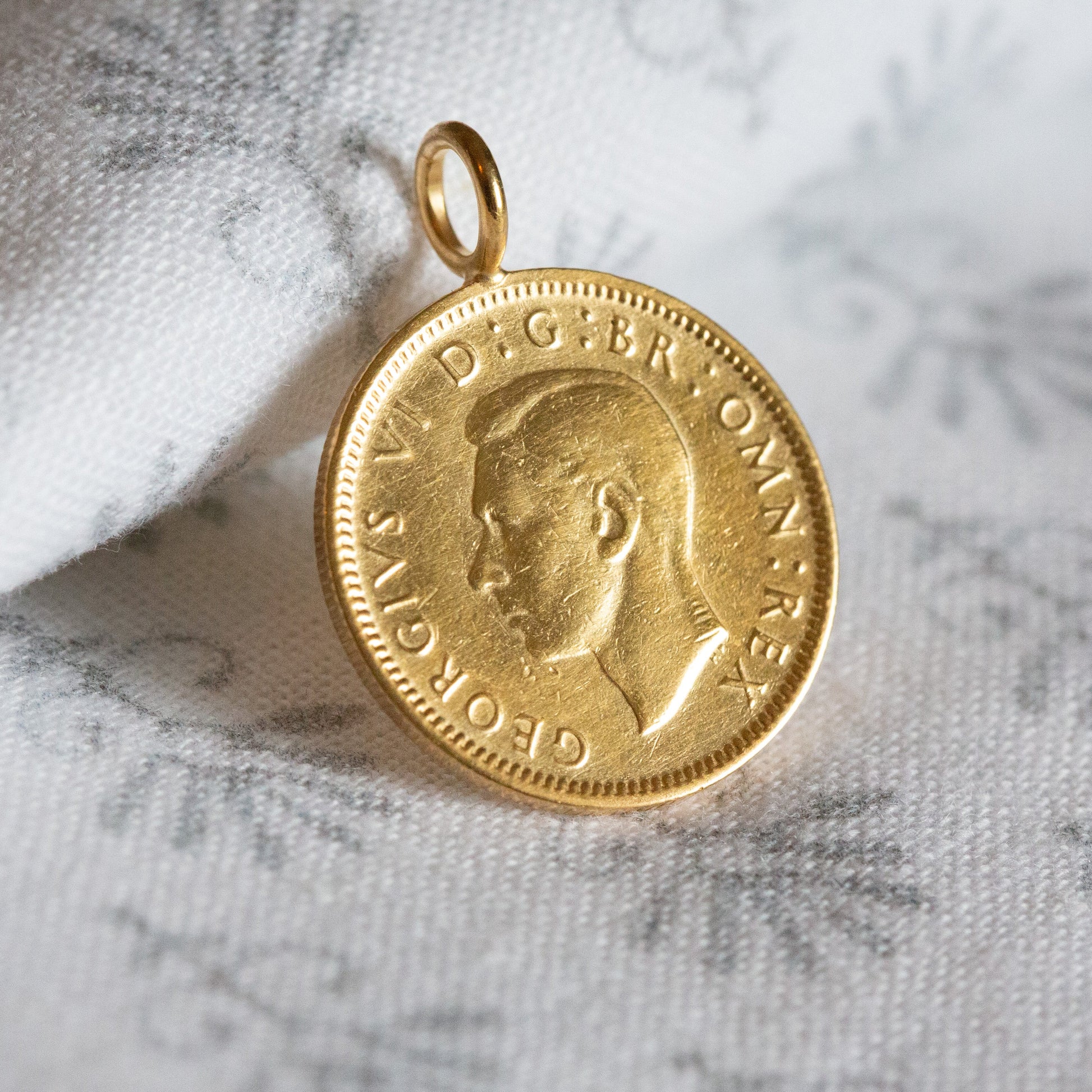 1948 gold coin pendant, sixpence coin, British coin, George VI on a light cotton background