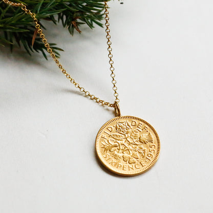 A sixpence coin pendant with 22carat gold plating sits on a white background with vermeil chain and fir tree details. Part of the Prenoa sixpence Christmas range gifts for her. 