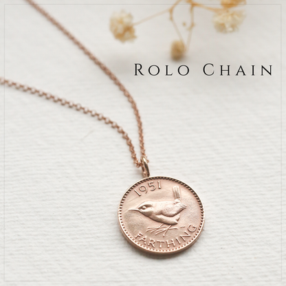 Rose gold rolo chain necklace with a coin pendant featuring a bird design on a light background.