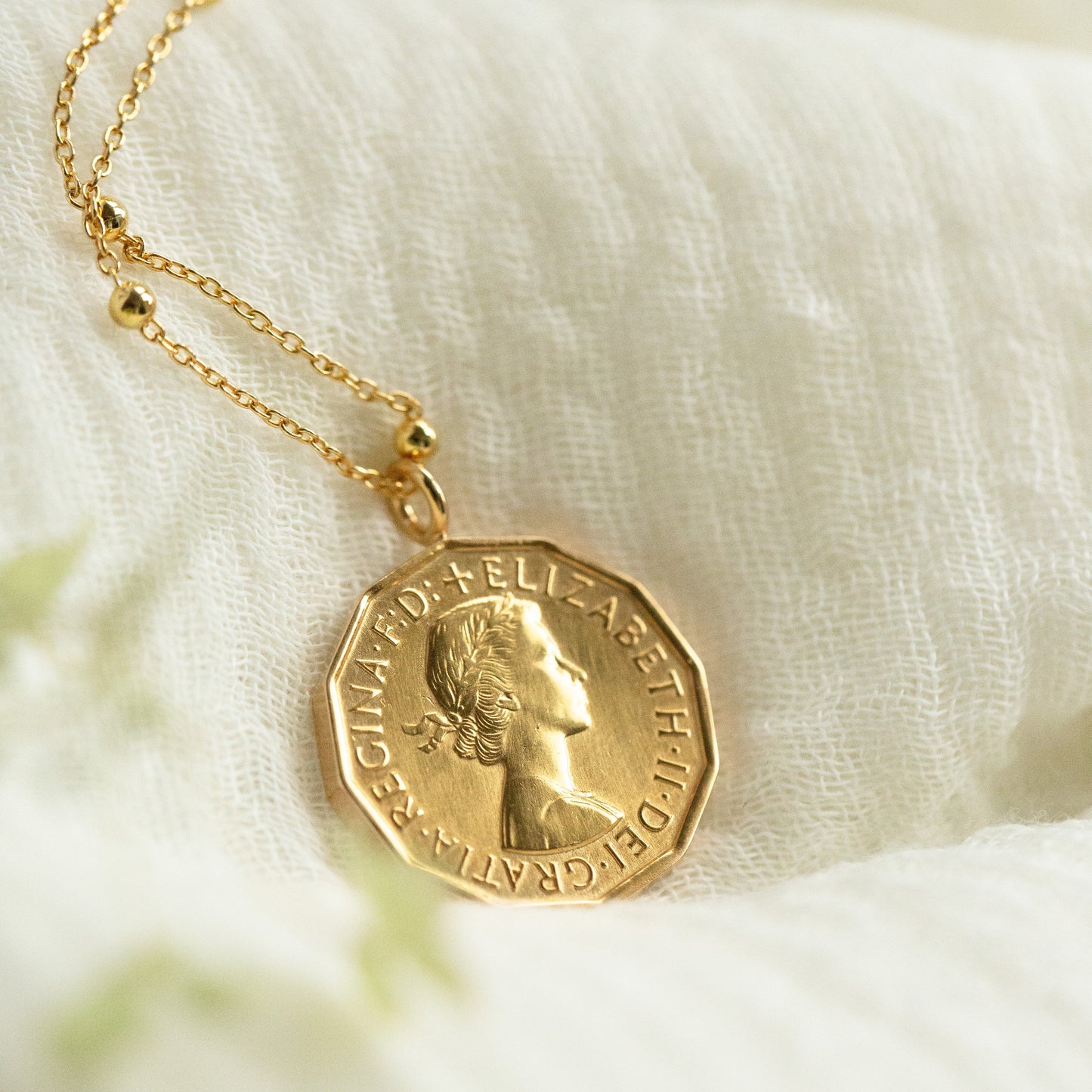 Gold coin necklace on a white fabric background