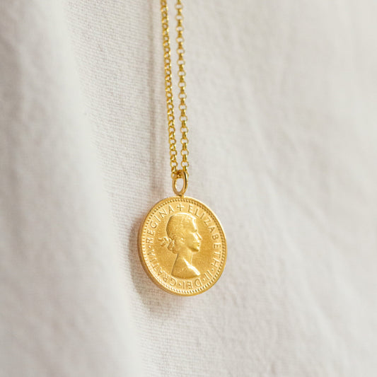 Gold necklace with a coin pendant on a white fabric background