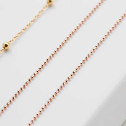 Two gold necklaces on a white surface