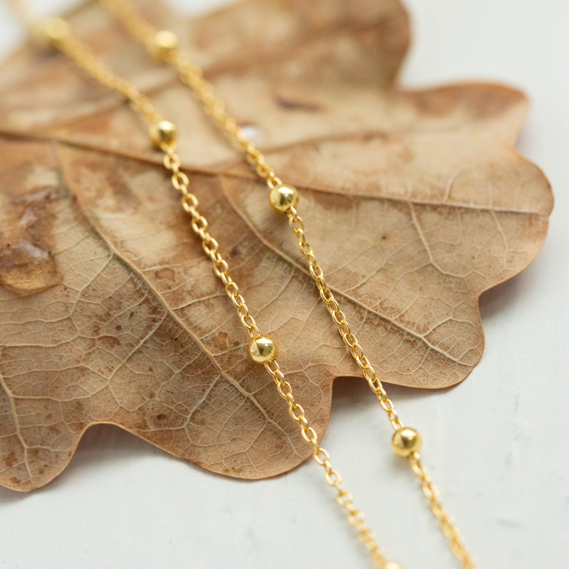 Gold vermeil satellite chain on a leaf.