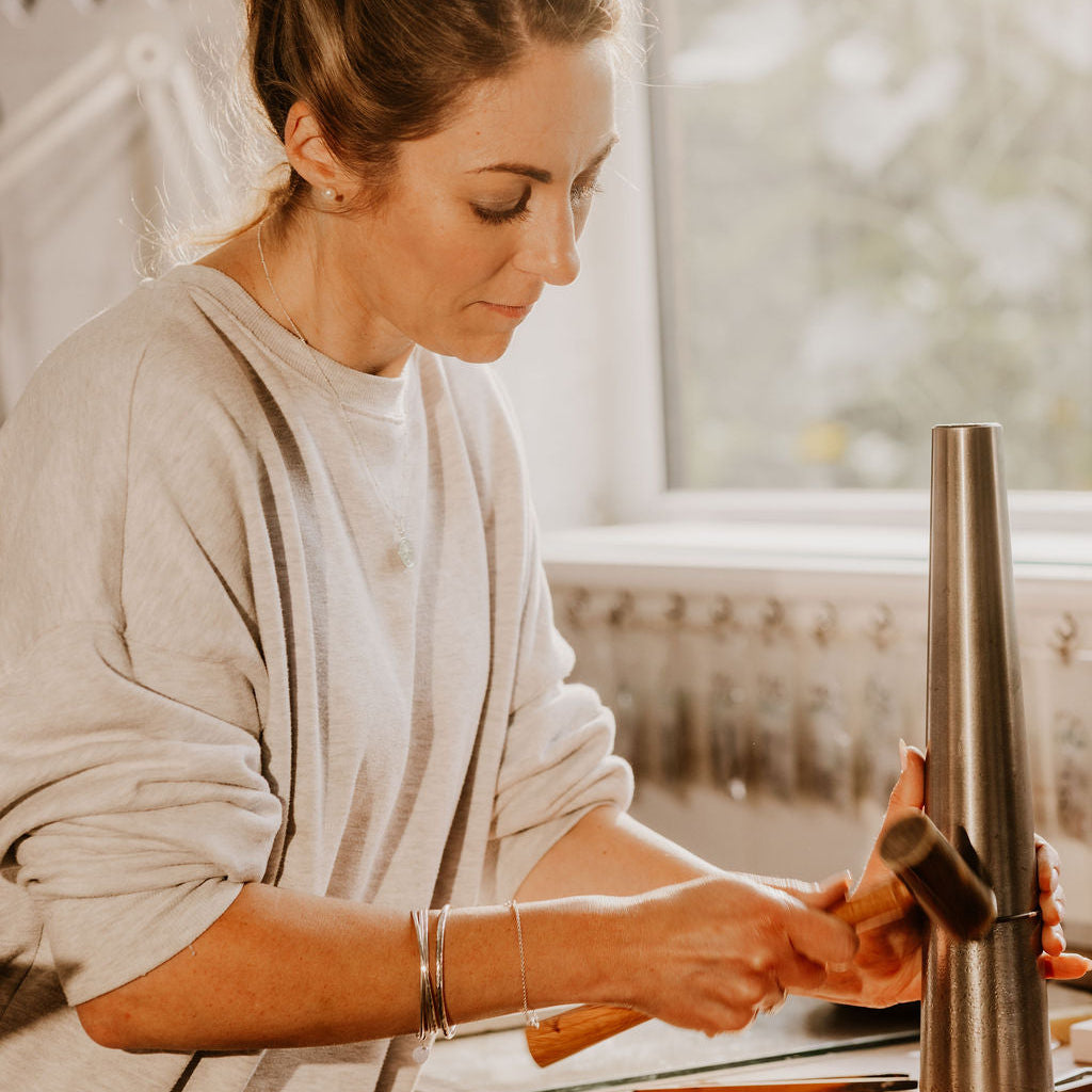 Becky works in the Prenoa workshop and adds the hammered patina to our sterling silver infinity bangles.
