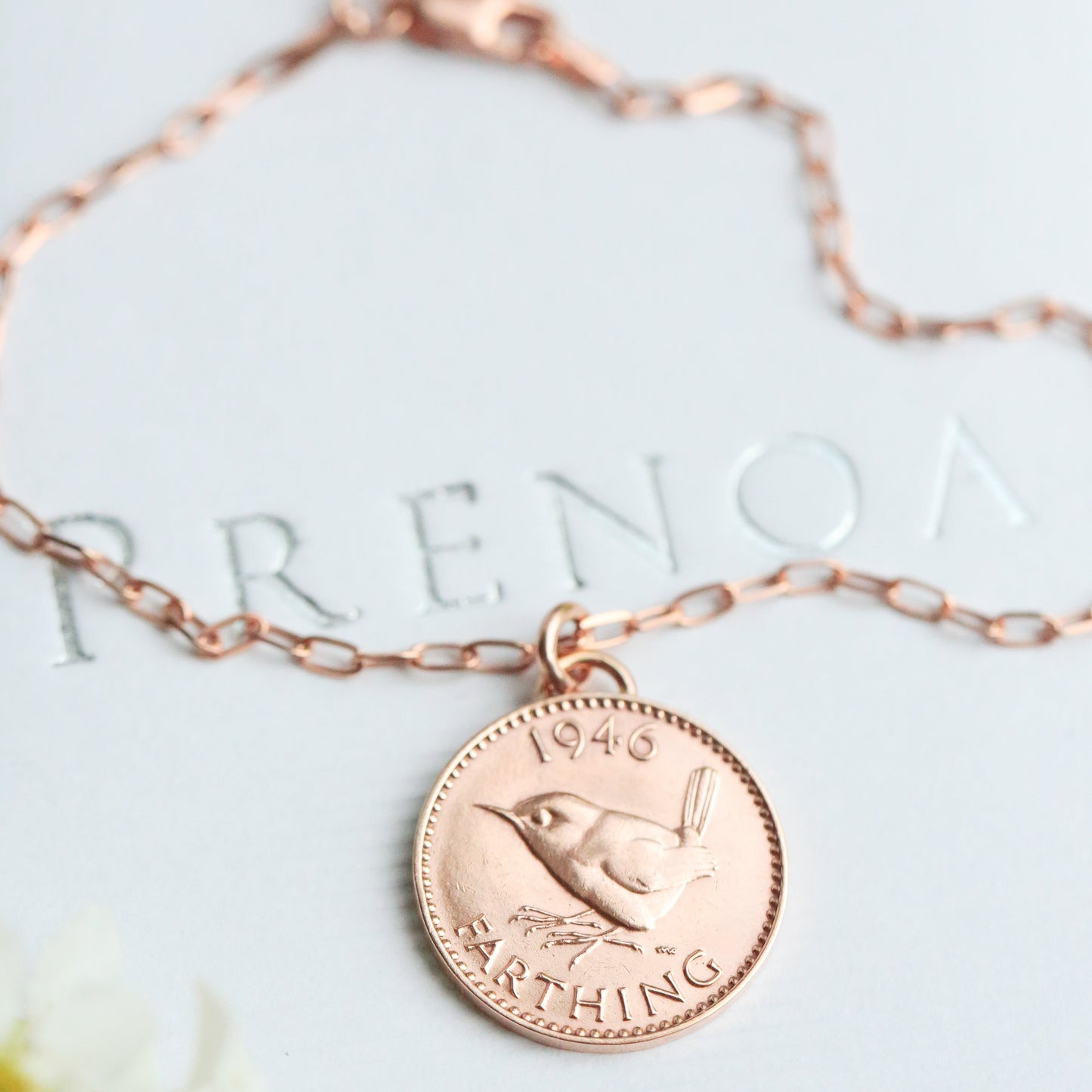 Rose gold coin necklace on a white box with a real Jenny Wren farthing and rose gold vermeil fine paperclip chain. 