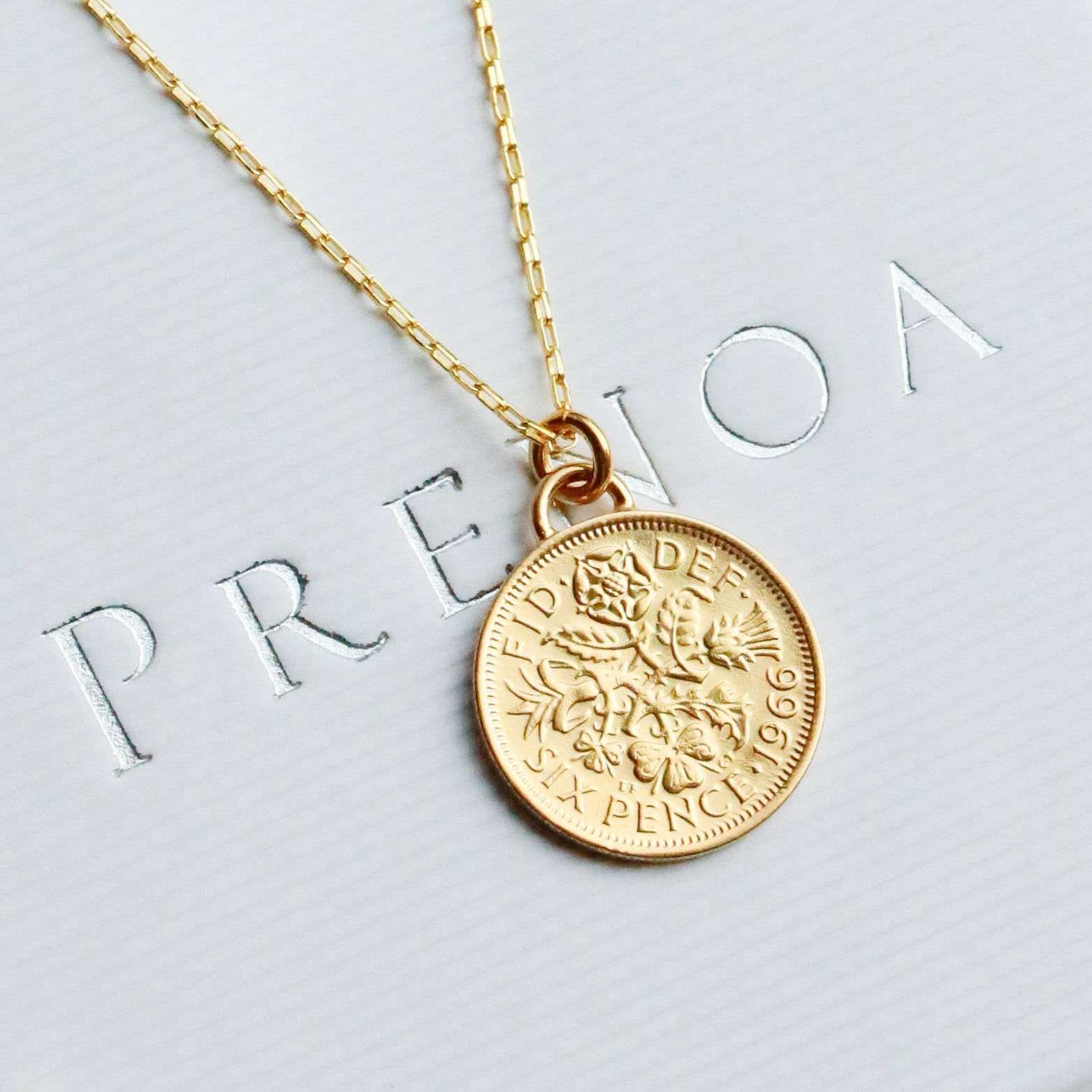 Gold sixpence coin 1966 dated necklace on a white box with flowers around