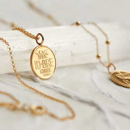 Gold necklace with a pendant on a white fabric background