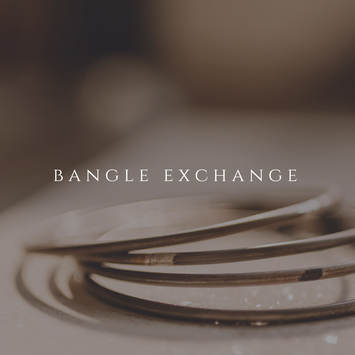 Close-up of a bangle with 'Bangle Exchange' text overlay on a blurred background