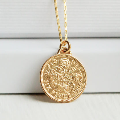 Gold sixpence 1956 necklace with a round pendant on a white surface