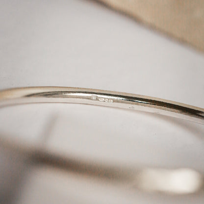 Close-up of a silver bracelet on a neutral background