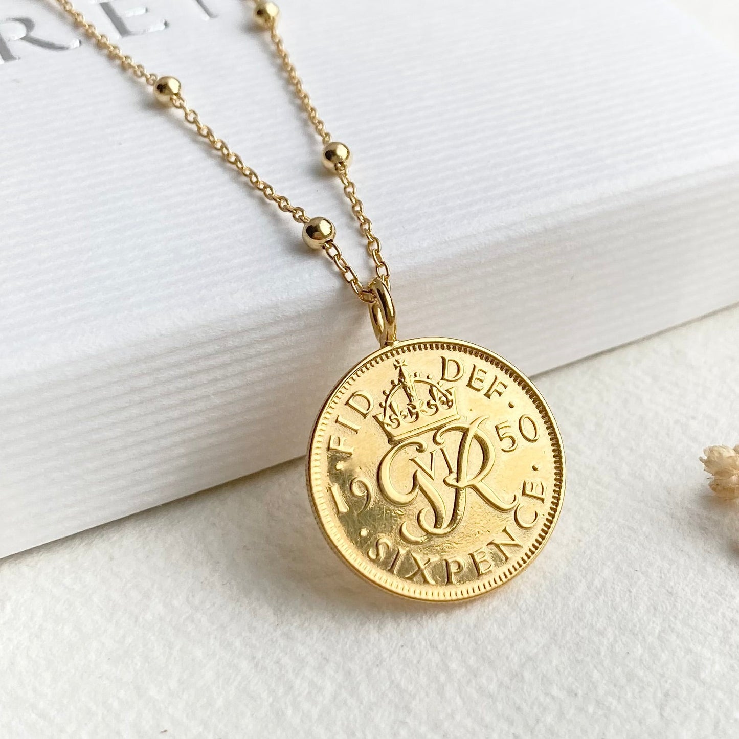 Gold necklace with a coin pendant on a white surface