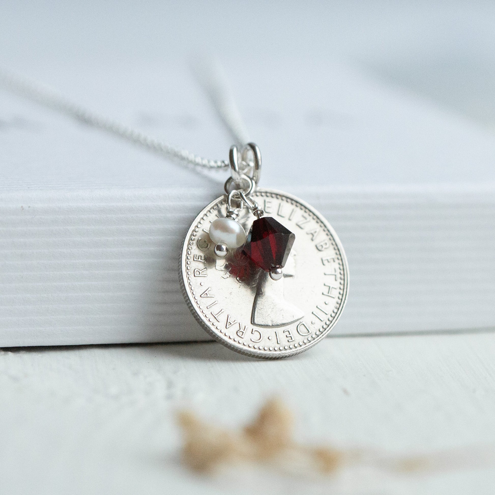 Sixpence coin necklace with a garnet January birthstone and pearl charm. 