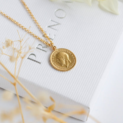 a gold coin necklace sits on a white background