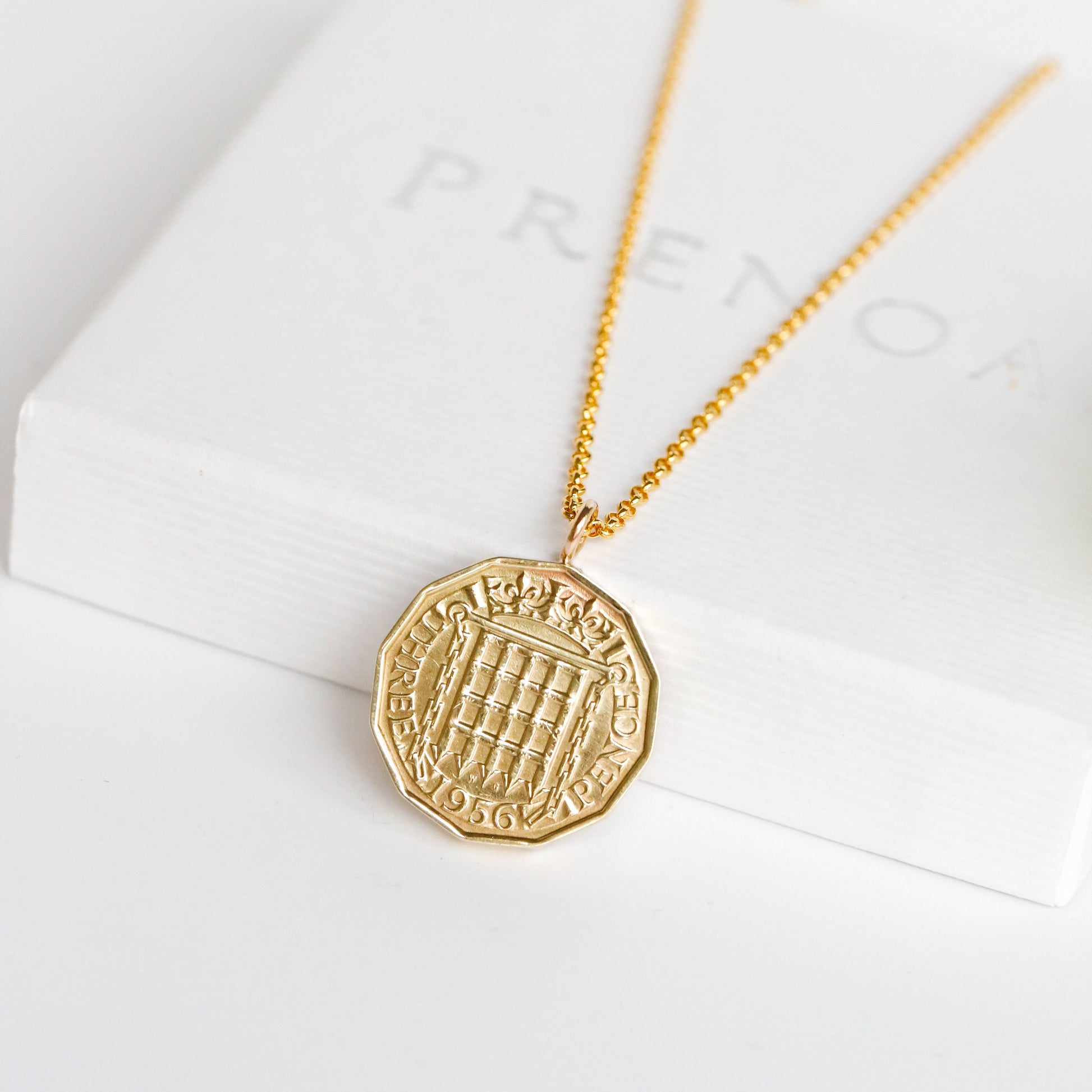 Gold necklace with a gold coin pendant on a white background. 1956 date coin jewellery