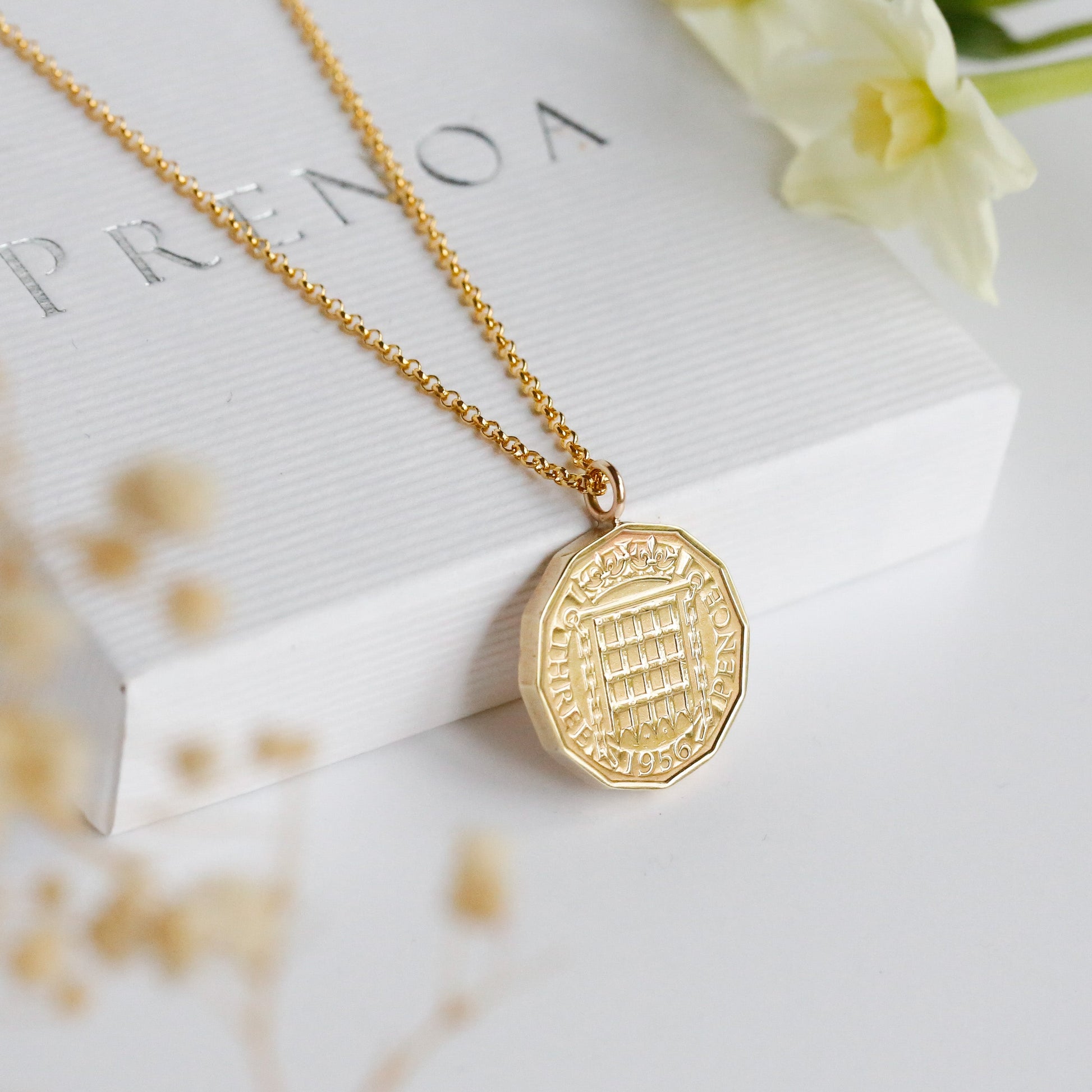 1956 British gold coin necklace, made in the UK with a real coin and precious metal chain and bail. White background with floral input.