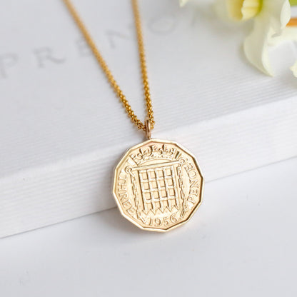 A British threepence gold coin pendant with precious metal gold chain sits on a Prenoa white gift box. 