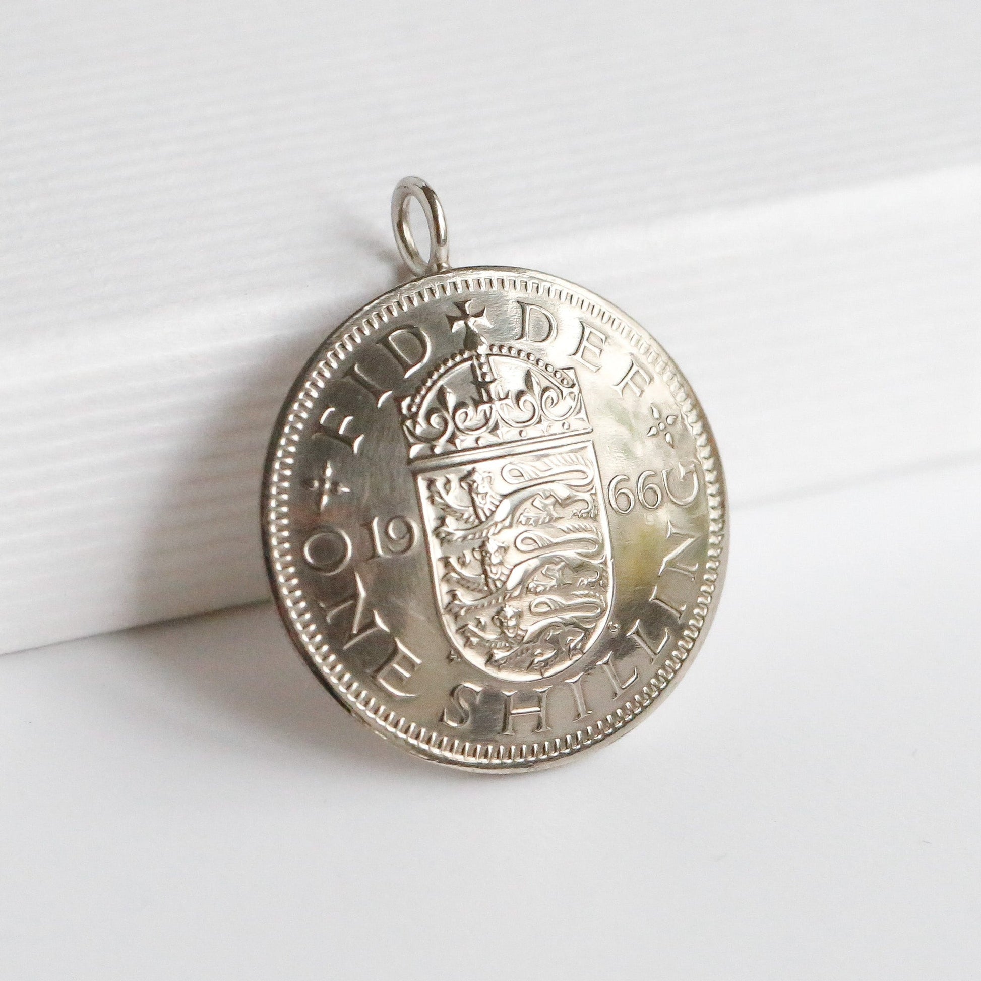 1966 dated British shilling pendant with a domed effect. Sitting on a white background. 