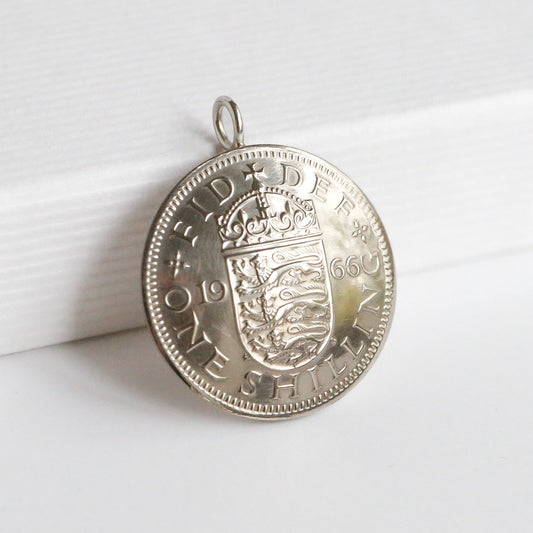 1966 dated British shilling pendant with a domed effect. Sitting on a white background. 
