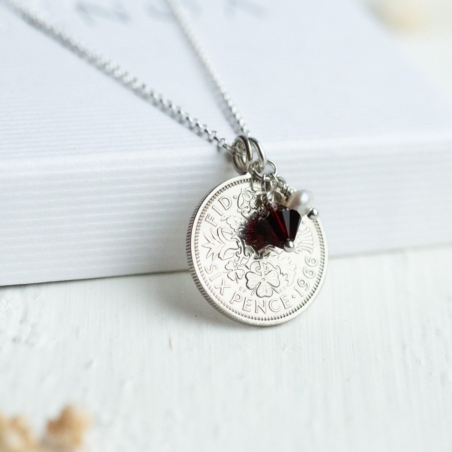 Silver coin sixpence necklace with a birthstone charm, round pendant on a white surface
