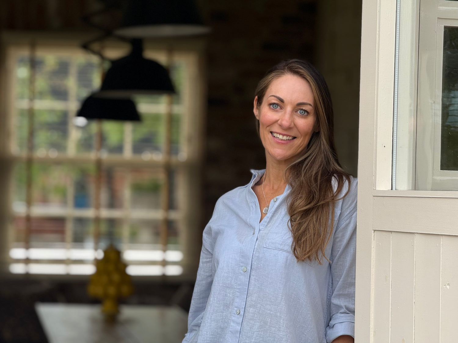Photo by ImTomColeman. 
Rebecca is standing in the doorway of the cottage dining room, in a pale blue shirt and Prenoa threepence silver coin necklace. 