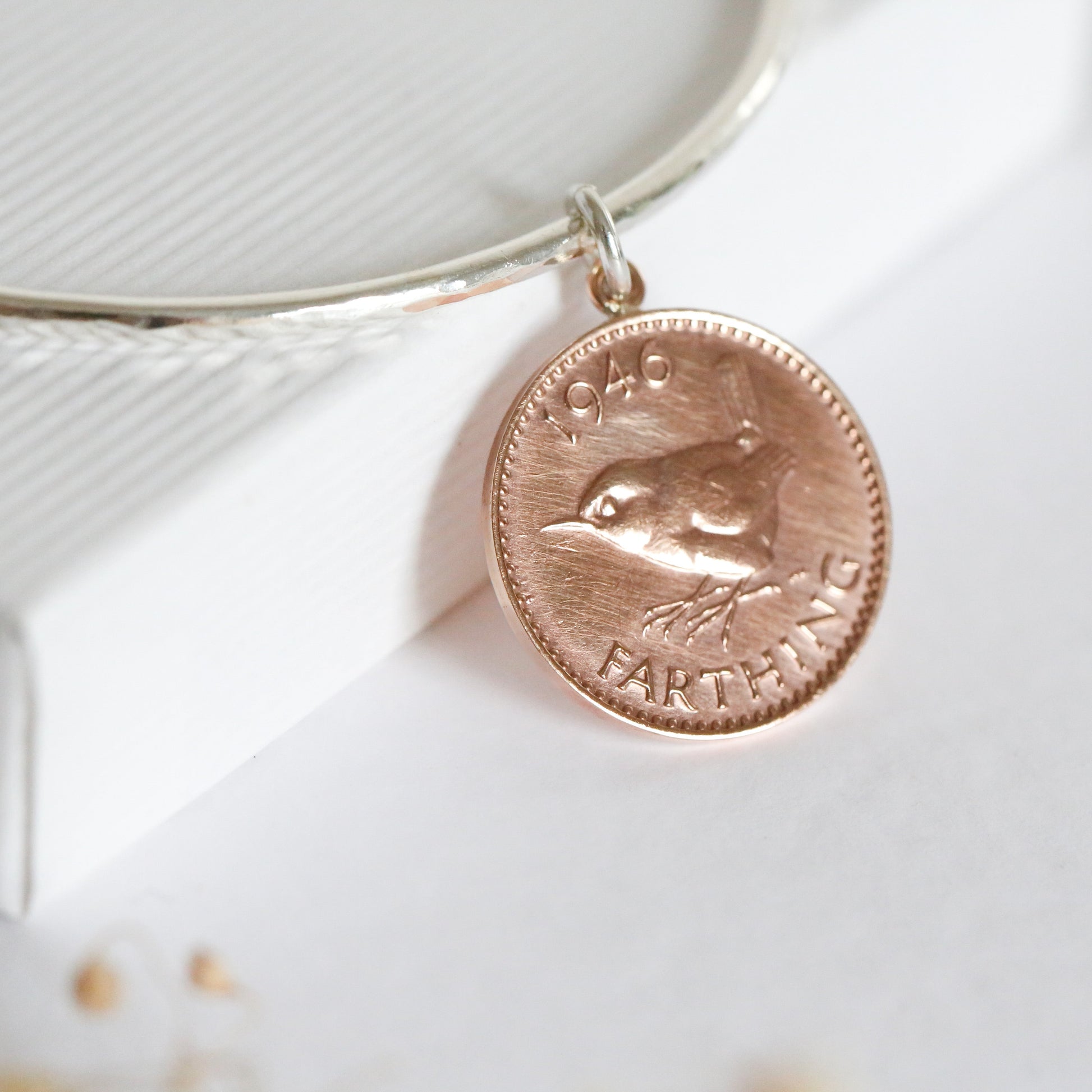 Bangle with a coin charm on a textured white surface