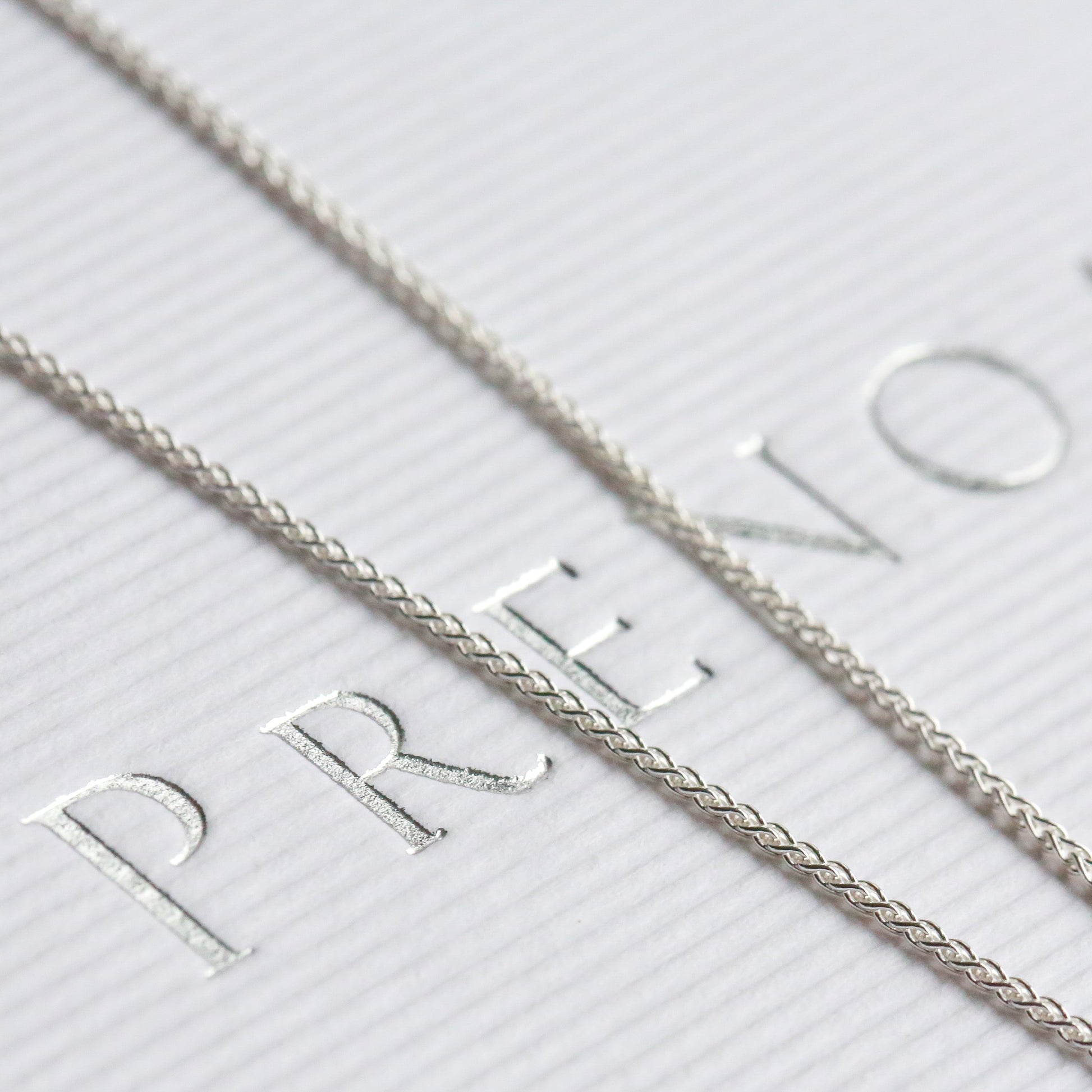 Silver necklace on a white box with 'PRENOA' branding.
