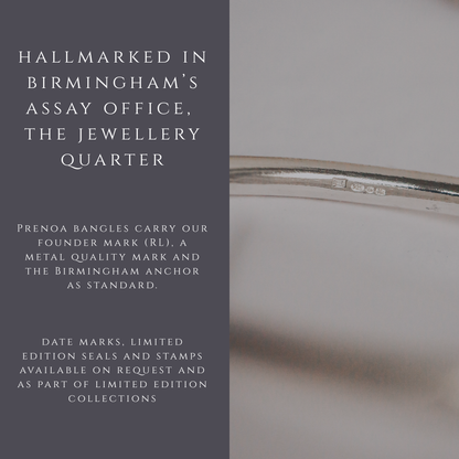 Silver bangle with hallmarking details on a gray background