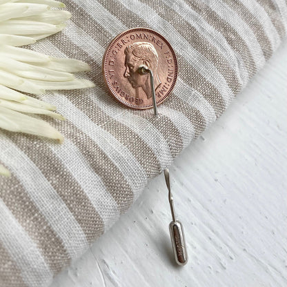A bronze farthing lapel pin sits on a linen background. Handcrafted in Stamford UK using real British coins.