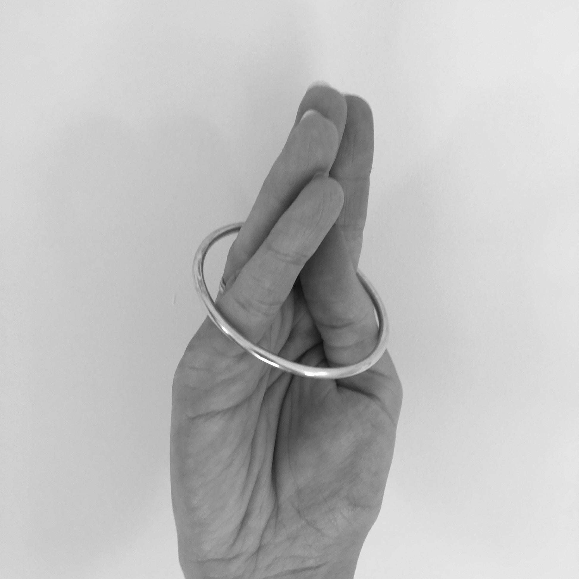Cone fingers together, and place bangle over the fingers. The bangle must pass over the widest part of the hand, the knuckles, when sizing correctly.