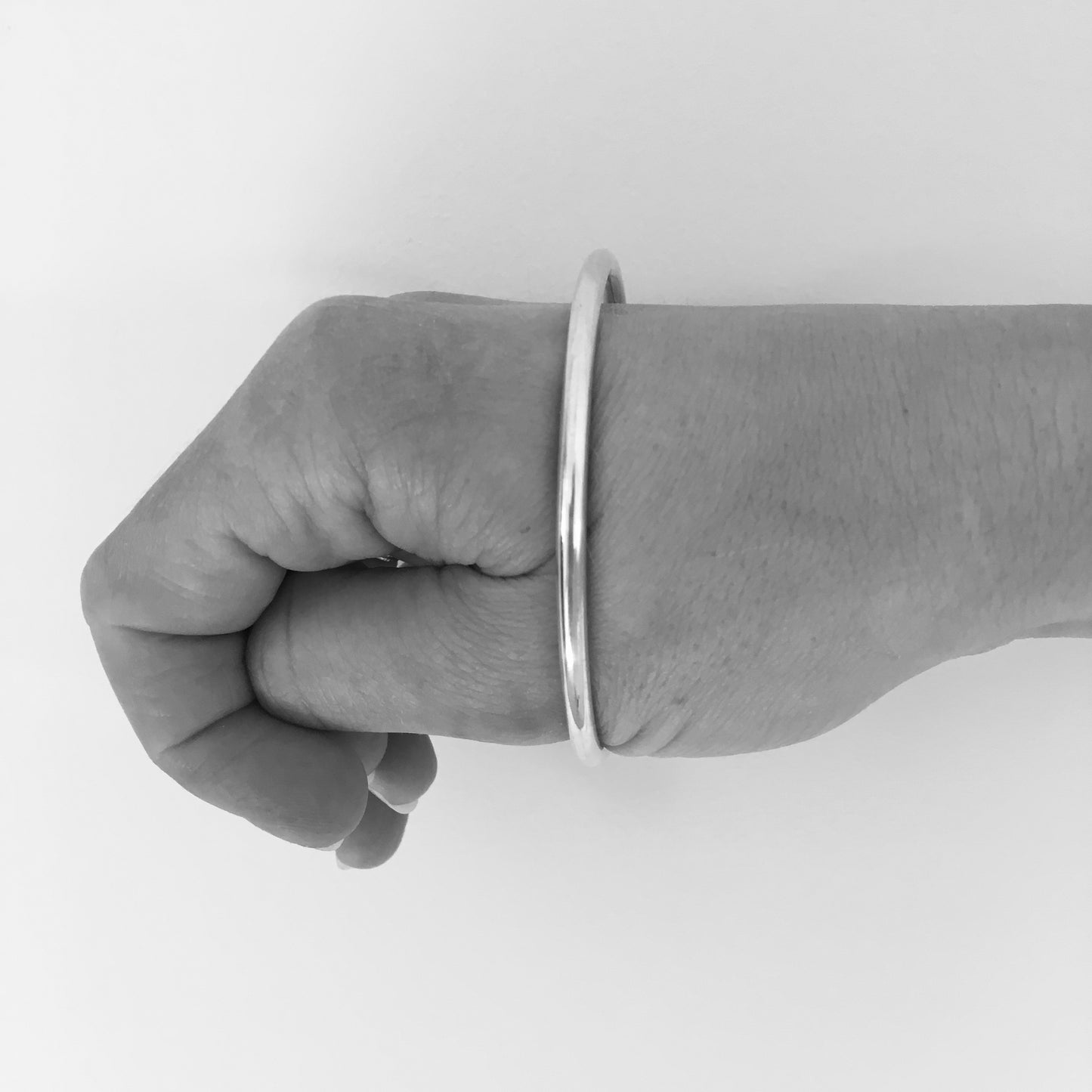 Once the bangle is over the knuckles, it should slide onto the wrist with a snug but comfortable fit